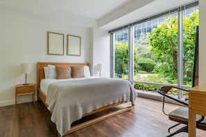 Une chambre avec une grande fenêtre, un lit, un bureau et une chaise.