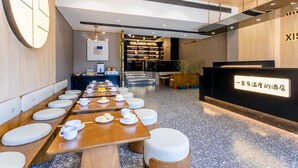 Una hall d'hotel moderna con un lungo tavolo da pranzo, sedute confortevoli e una reception.