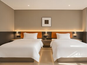 Ein Hotelzimmer mit zwei Betten, einem Nachttisch, einer Wandleuchte und einem gerahmten Bild.