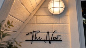 Et hjørne af en bygning med en lampe og et skilt, der siger 'The Nest'.