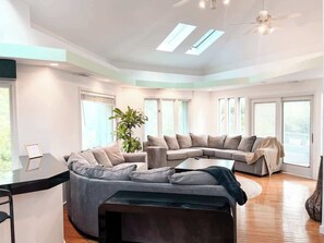 A modern living room with a sectional sofa, a coffee table, and a desk with a computer.