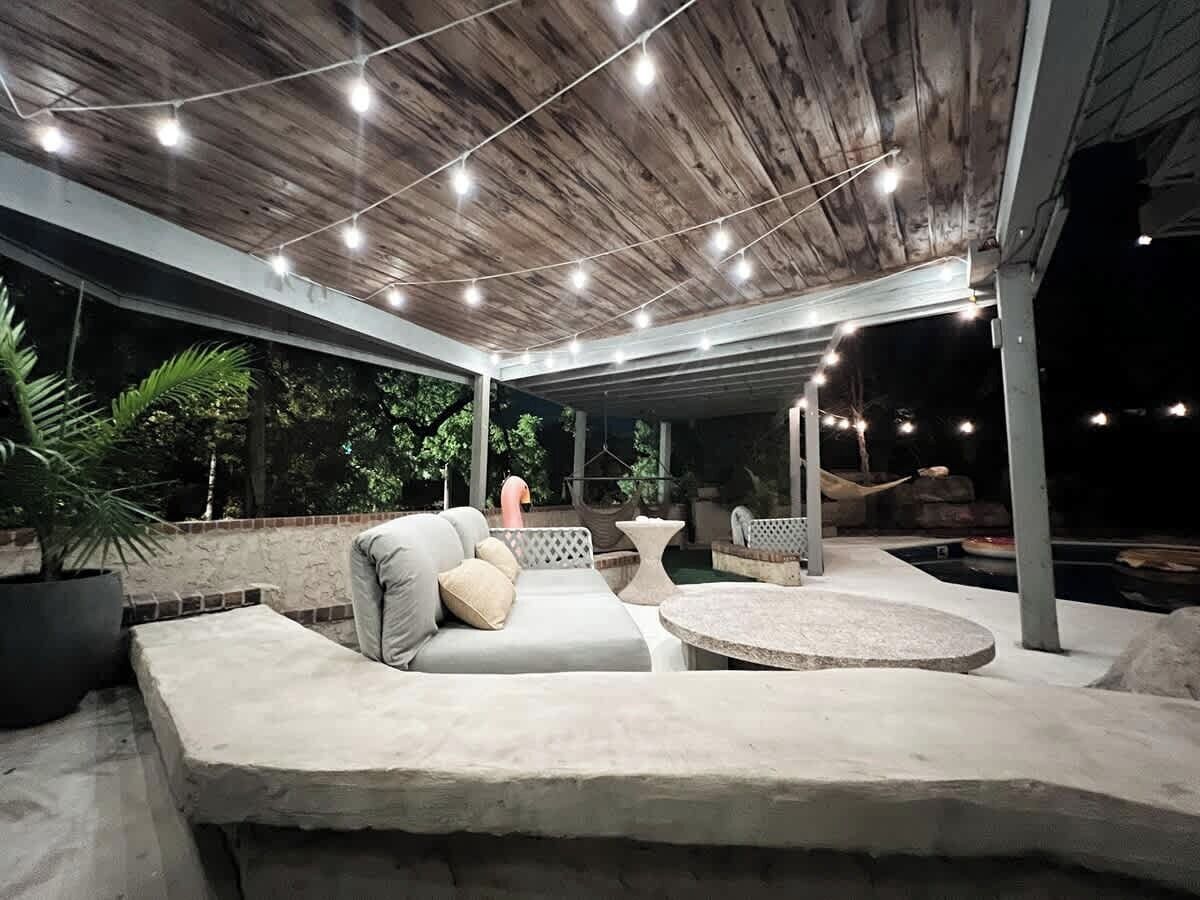 An outdoor patio area with a sofa, a round table, and string lights.