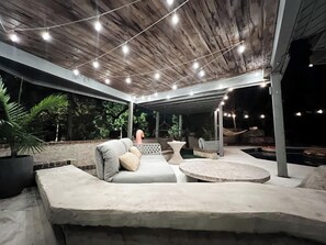 An outdoor patio area with a sofa, a round table, and string lights. - One of a Kind_Family Stay_Space For All_HotTub (Kansas City)