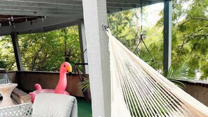 A hammock under a covered area with a wooden bench and a pink flamingo inflatable. - Luxury  Villa w/ Pool, Max Amenities (Kansas City)