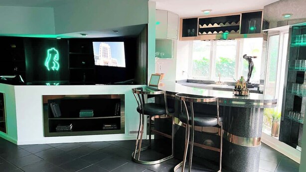 A modern kitchen with a bar area, built-in entertainment unit, and a large window. - Luxury  Villa w/ Pool, Max Amenities (Kansas City)