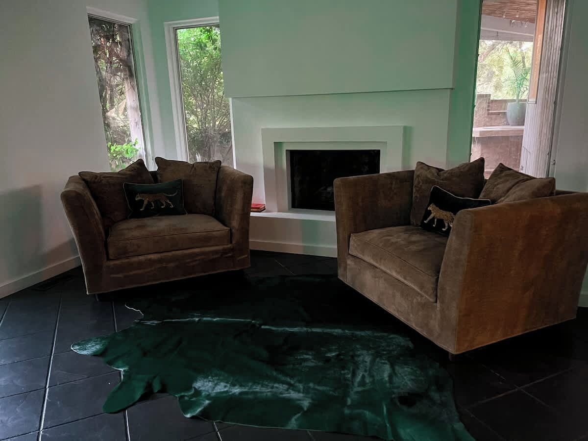 Ein Wohnzimmer mit zwei Sofas, einem Kamin und einem großen, grünen Teppich.