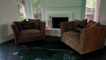 Ein Wohnzimmer mit zwei Sofas, einem Kamin und einem großen, grünen Teppich.