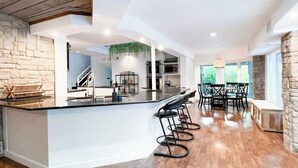 A spacious kitchen with a central island, bar stools, and a dining area with a table and chairs. - Luxury  Villa w/ Pool, Max Amenities (Kansas City)