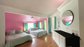 A bedroom with two beds, a desk, a mirror, and a ceiling fan.