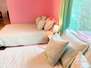 A bedroom with two beds, a nightstand, and a lamp.