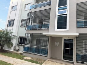 A multi-story residential building with balconies, a visible 'W' sign, and a small lawn area. - Palma real  (Puñal)