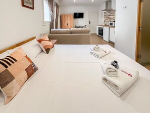 Ein Hotelzimmer mit Bett, einer Couch, einem Fernseher, einer Küchenzeile und einer Tür.