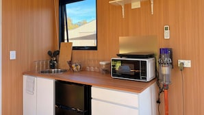 A compact kitchenette with a microwave, kettle, and a small shelf with a kettle and a cup. - Tiny Home in the Hills by Tiny Away (Forrestfield)