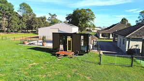 A residential area with a small wooden structure, a metal shed, and a house with a tiled roof. - Tiny Home in the Hills by Tiny Away (Forrestfield)