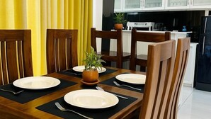 Un'area pranzo con un tavolo di legno apparecchiato per quattro persone, circondato da sedie.