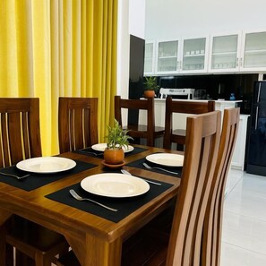 Comedor con una mesa de madera preparada para cuatro personas, rodeada de sillas.