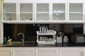 Una cocina con armarios blancos, un lavamanos y un escurreplatos.