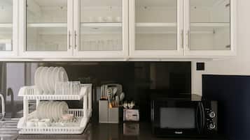 A kitchen with white cabinets, a dish rack, a microwave, and a coffee maker.