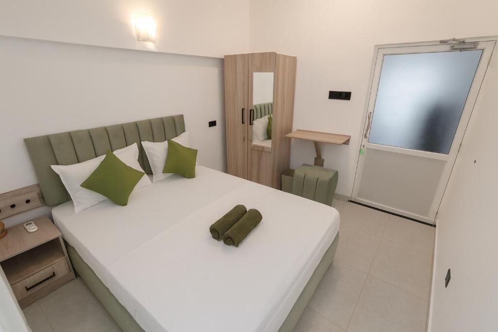 A hotel room with a bed, a nightstand, a wardrobe, a mirror, and a door.