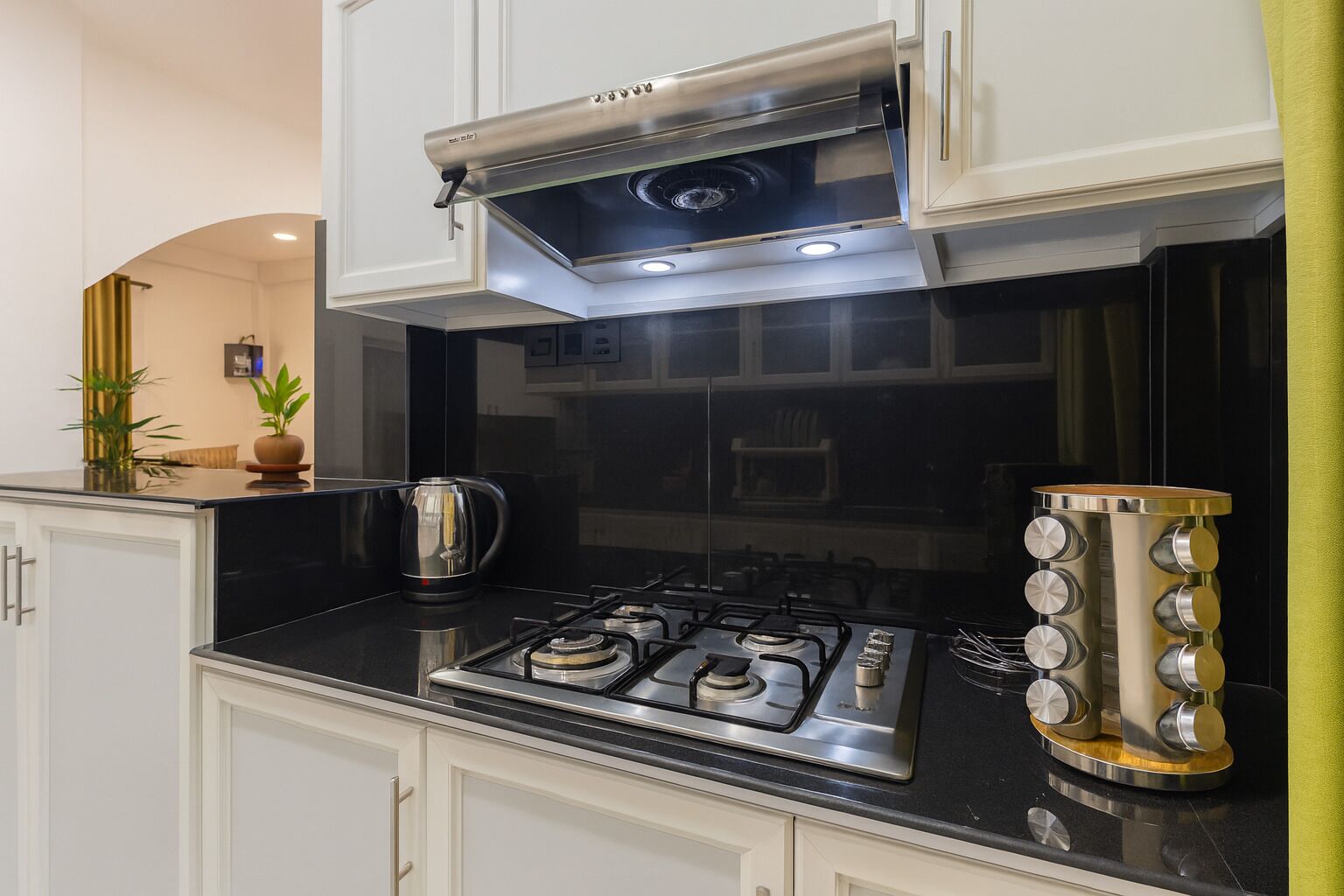 A modern kitchen with a gas stove, stainless steel range hood, and a coffee maker.