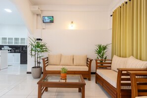 A modern living room with a sofa, two armchairs, a coffee table, and potted plants. - Skyport Villa Katunayaka (Katunayake)