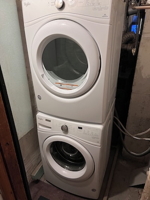 A stacked washer and dryer unit with control panels and a hose. - Peaceful St. Pete 2BR Home with Tropical Garden (St. Petersburg)