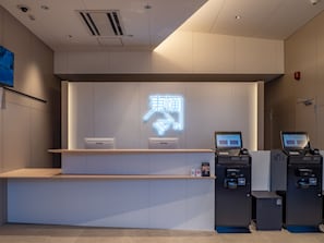 A reception desk with a neon sign, two computers, and a trash bin. - Toyoko Inn Toyohashi Ekimae Odori (Toyohashi)
