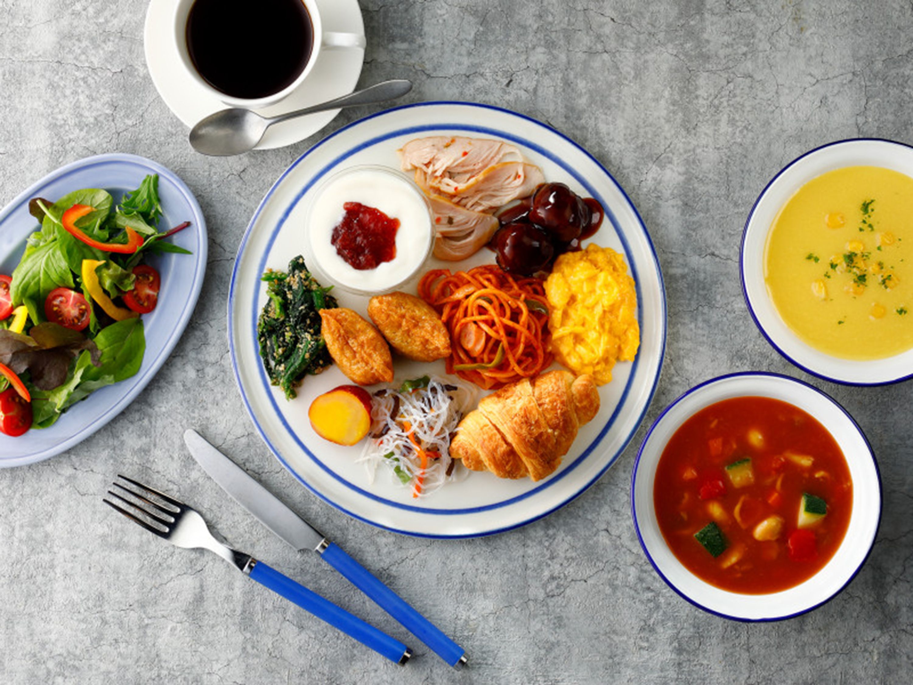 Una mesa con diversos platos, incluyendo ensalada, huevos y sopa.