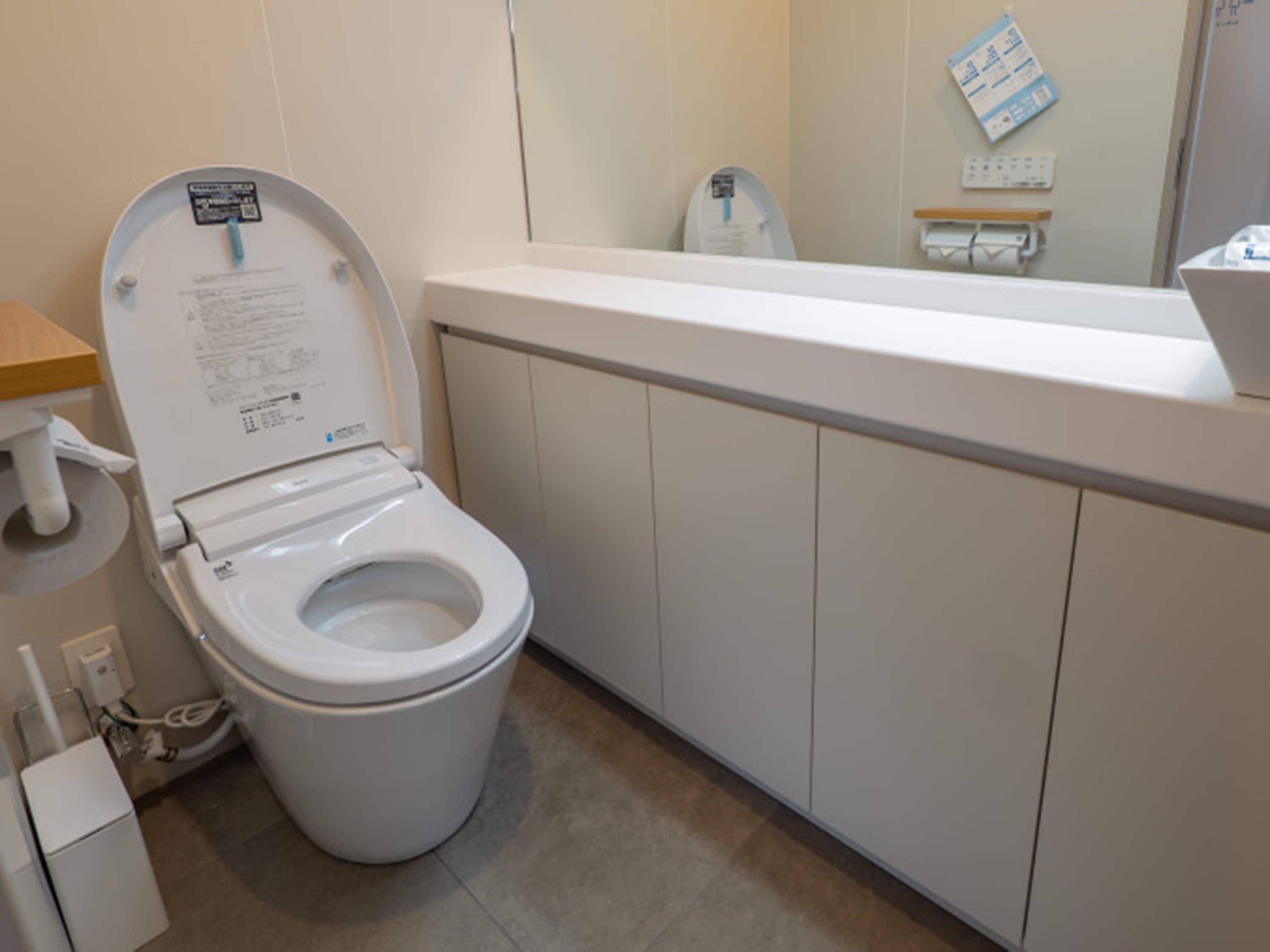 Un baño moderno con inodoro, lavamanos y espejo.