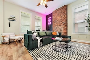 A modern living room with a sectional sofa, a coffee table, and a striped rug. - Netflix+BBQ+Free Parking Near Shops in East Liberty (Pittsburgh)