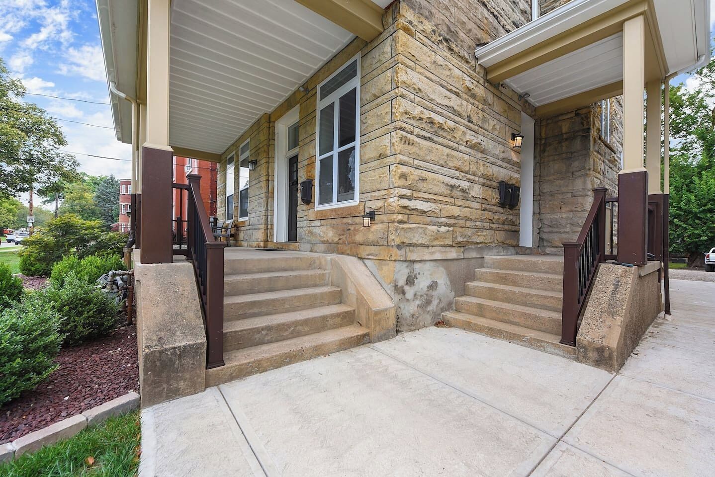 A stone building with a covered porch and a set of concrete steps leading to the entrance.