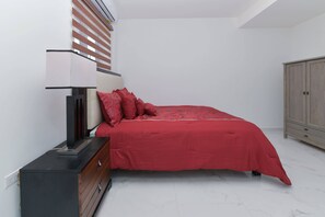 A bedroom with a bed, a nightstand, a lamp, and a wardrobe. - Sleek 2BR Retreat, Tanki Leendert (Tanki Leendert)