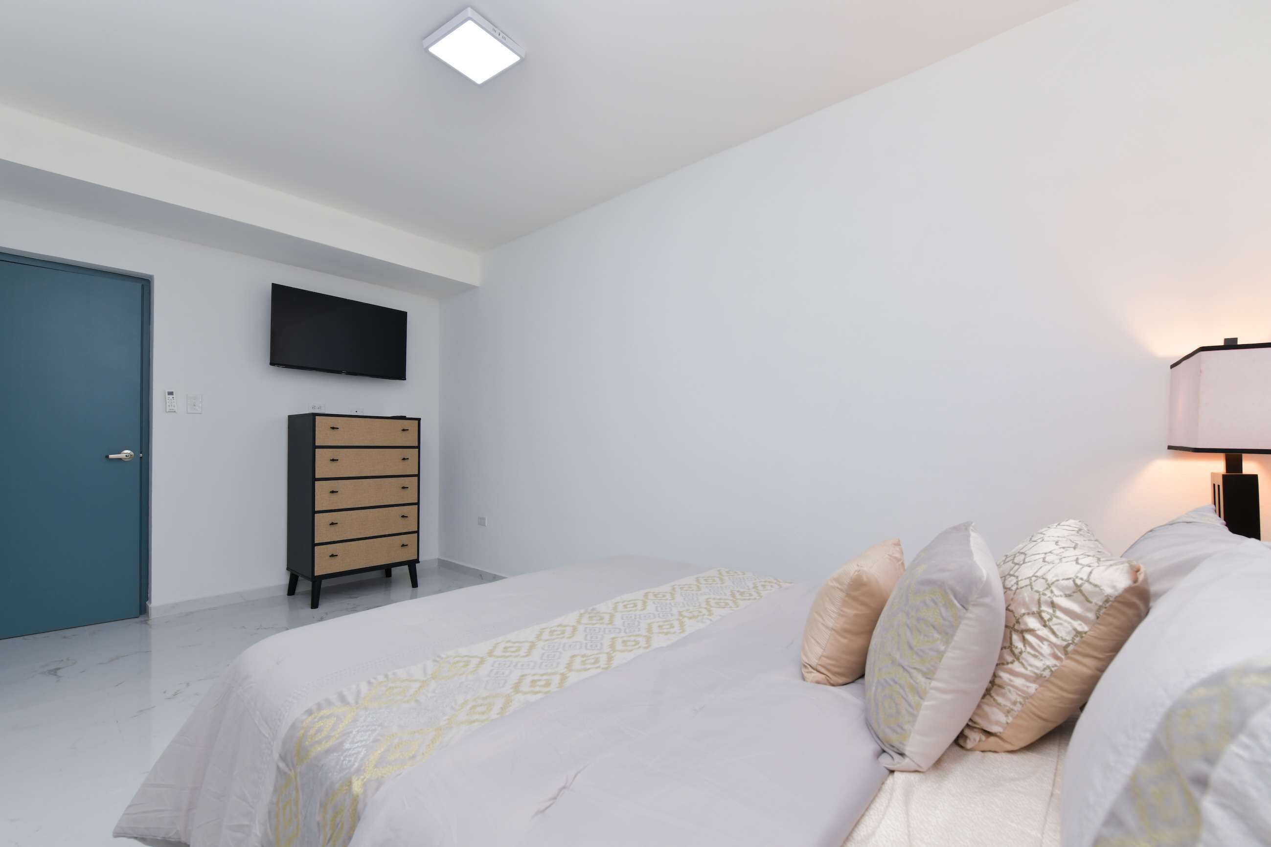 Ein Schlafzimmer mit einem Bett, einem Schminktisch, einem Fernseher und einer Tür.