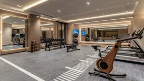 Ett gym med flera våningsplan, utrustat med löpband, motionscyklar och styrketräningsmaskiner.