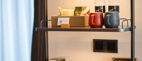 A hotel minibar with a coffee maker, tea kettle, and a box of tea bags.