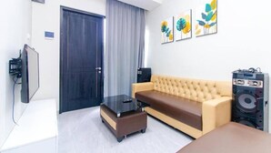 Una sala de estar con un sofá, una mesa de centro, una televisión y obras de arte en la pared.