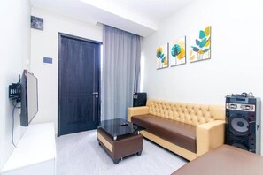 A living room with a sofa, a coffee table, a television, and artwork on the wall. - Cozzy Villa Tera (batu)