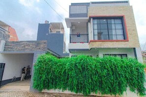A modern two-story residential building with a balcony and a large window. - Cozzy Villa Tera (batu)