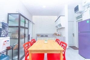 A compact kitchen with a dining table, chairs, and a refrigerator. - Cozzy Villa Tera (batu)