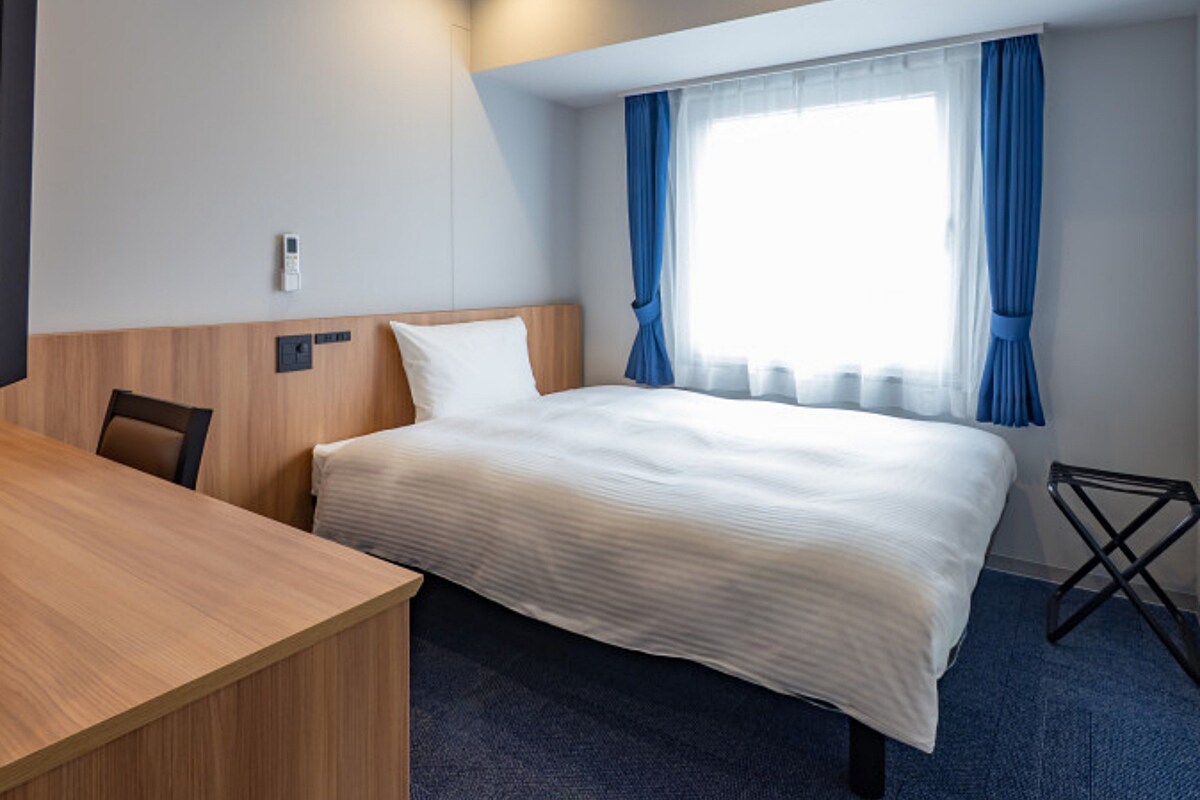 Una habitación de hotel con una cama, un escritorio y una silla.