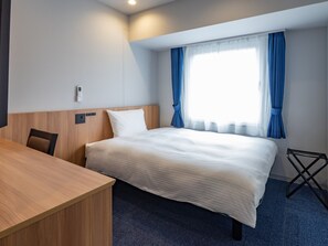 Una habitación de hotel con una cama, un escritorio y una silla.