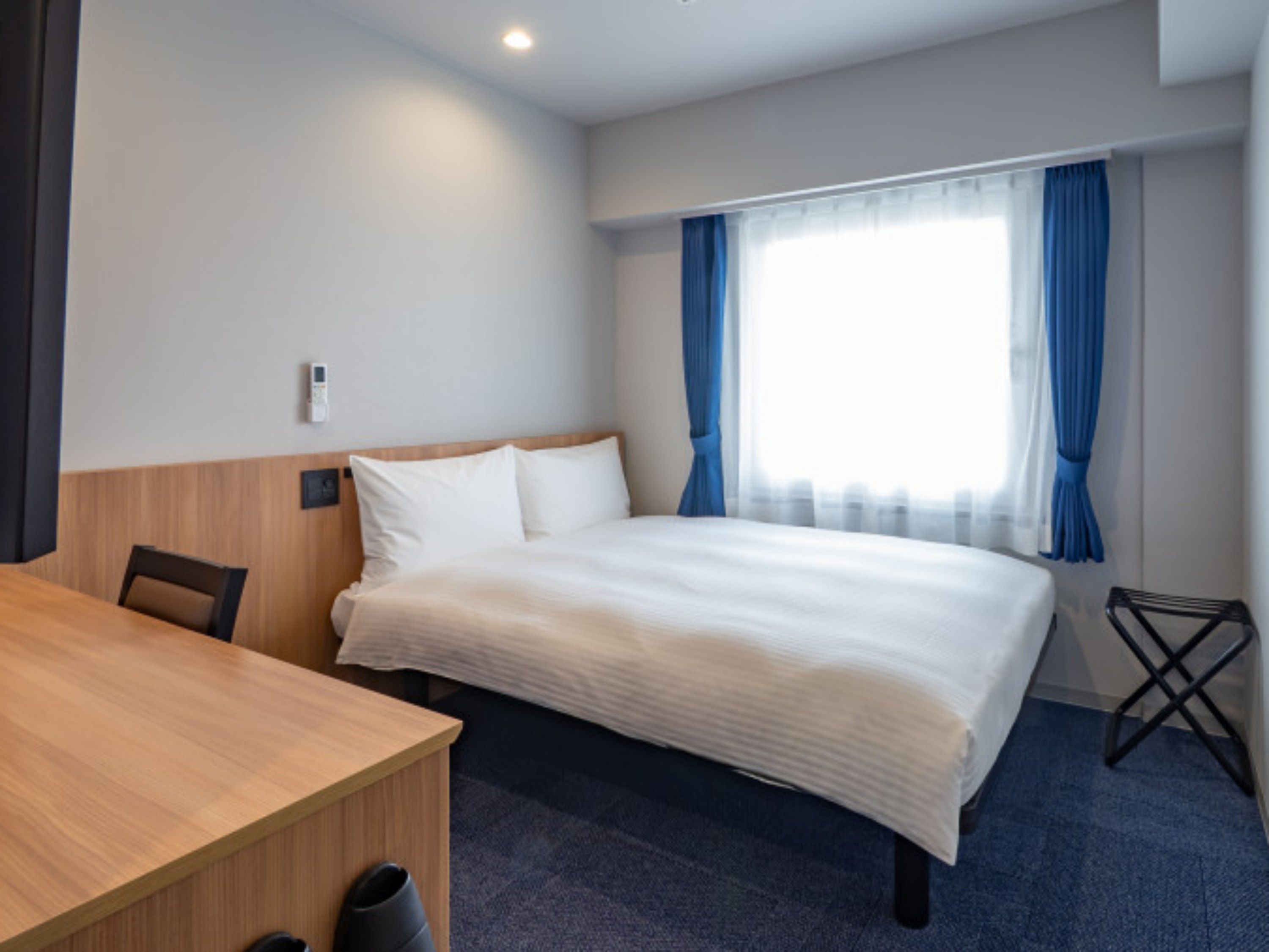 Una habitación de hotel con una cama, un escritorio y una silla.