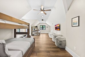 Ein modernes Schlafzimmer mit Etagenbett, Deckenventilator und Blick ins Freie durch ein Fenster.