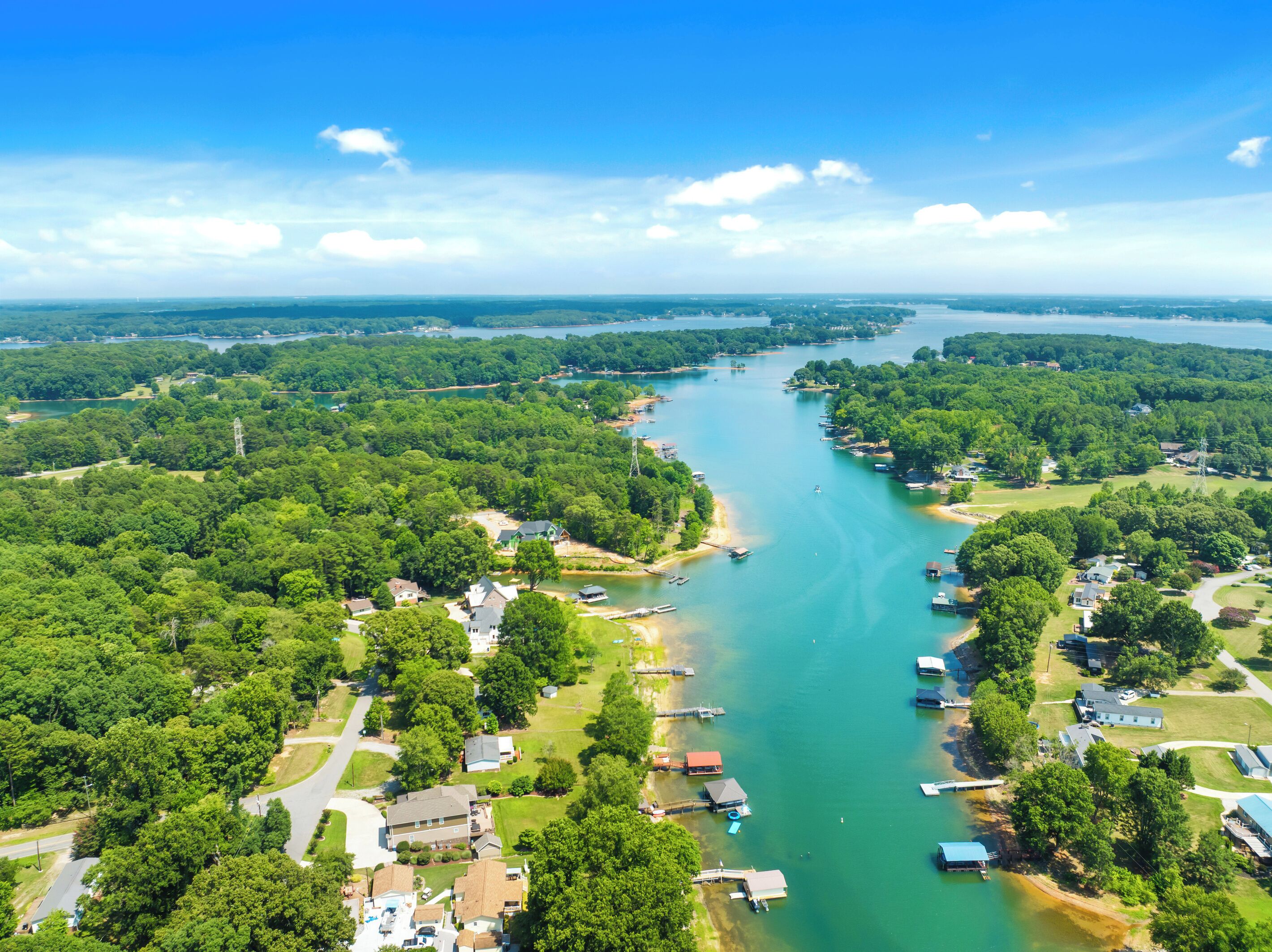 Vista aérea de un río con barcos, rodeado de vegetación densa y zonas residenciales.