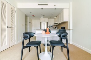 A compact kitchen with white cabinets, a round table, and four black chairs. - Blueground | Penn Quarter, pool, nr National Gallery (Washington, D.C.)