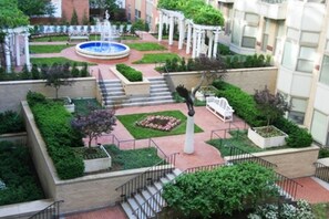 Ein Innenhof mit Brunnen, Stufen, Bänken und viel Grün.