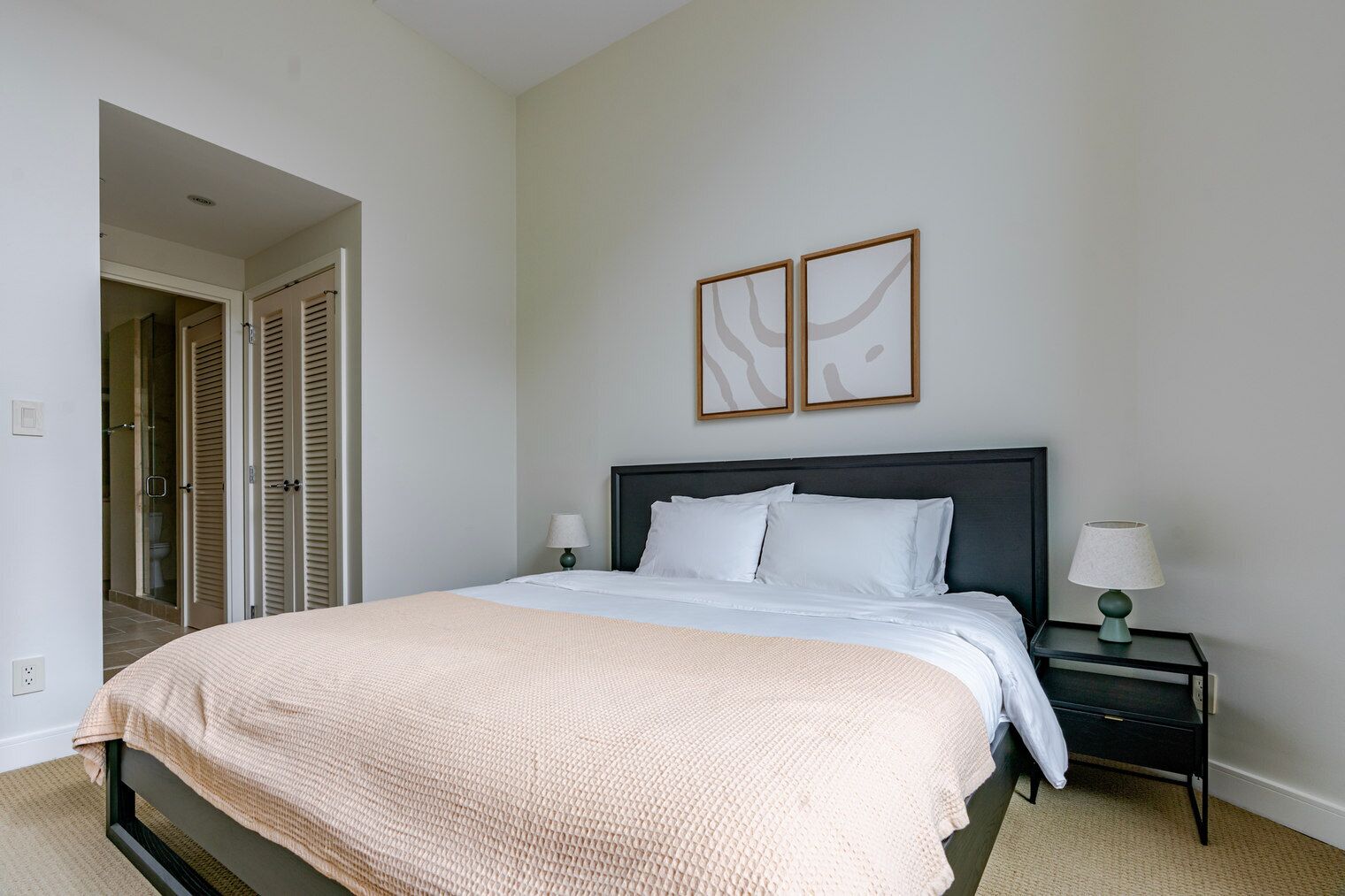 Ein Schlafzimmer mit einem Bett, Nachttischen und einer Tür zu einem Badezimmer.