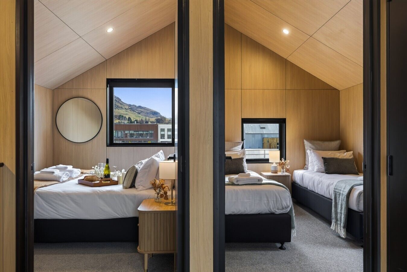 Une chambre moderne avec deux lits, une grande fenêtre et une vue sur un immeuble.