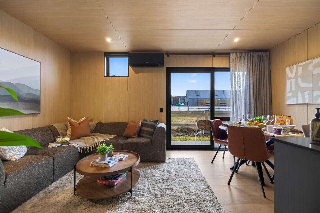 Een moderne woonkamer met een bank, salontafel en eethoek.