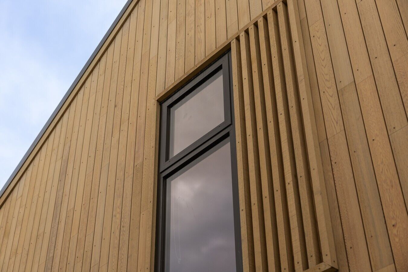 Een gebouw met een houten gevel en een groot raam.